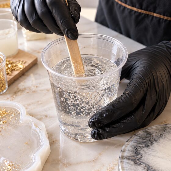 Mezcla de resina removida con un palito, con burbujas de aire atrapadas dentro del vaso